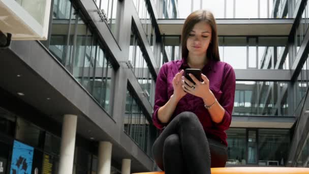 Säker affärskvinna tittar på mobiltelefon mot bakgrund av en byggnad — Stockvideo