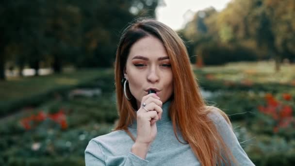 Blízký portrét červenejch žen kouří VAPE elektronickou cigaretu a fouká z úst pára — Stock video