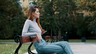 Güneşli parkta bankta kırmızı saçlı oyuncacık seksi kadın