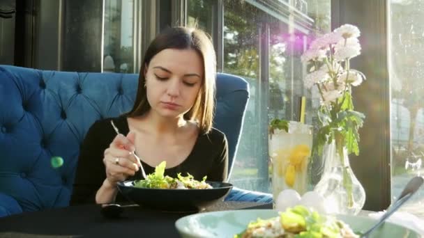 Allein schöne junge Frau isst einen heißen Salat in einem Restaurant allein bei Sonnenuntergang — Stockvideo