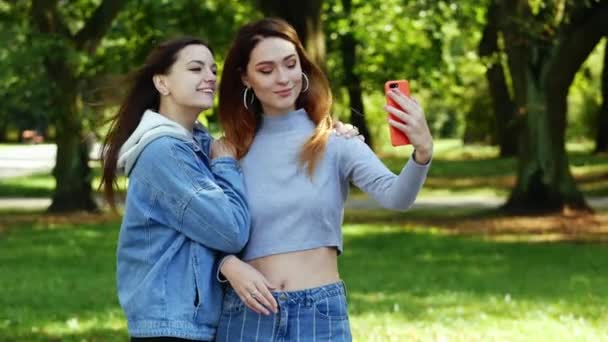 Dos mujeres felices hacen selfie en el teléfono móvil en el parque de la ciudad — Vídeos de Stock