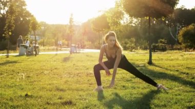 Spor yapan kadın spor yapıyor, aerobik yapıyor, esneme egzersizleri yapıyor, gün batımında parkta antrenman yapıyor, sağlıklı ve sportif yaşam tarzı kavramı.
