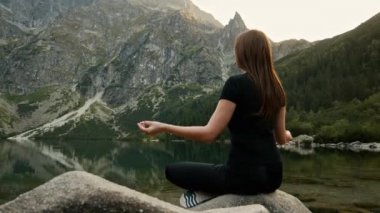Sağlıklı genç kadın bir dağ gölü üzerinde meditasyon, yoga pratik, dağlarda yüksek huzur sahiptir