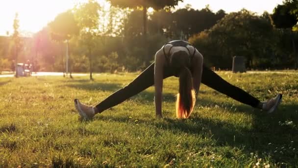 Mujer deportiva tratar de sentarse en un cordel, haciendo ejercicios de fitness y estiramiento, entrenamiento en el parque al atardecer, estilo de vida saludable y deportivo — Vídeo de stock