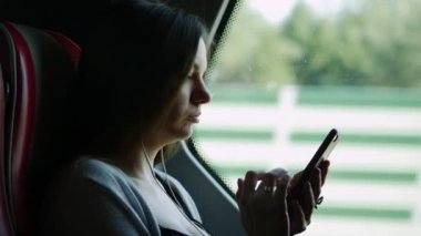 Otobüs yolculuğunda yalnız kadın seyahatyakın portre, müzik dinleme ve cep telefonu kullanımı