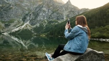 Kadın turist cep telefonu kullanmak, seyahat günlüğü için manzara fotoğraf çekmek veya kayıt video