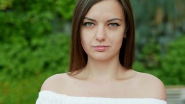 Güzel utangaç kadının yakın çekim portresi sokakta kameraya gülümsüyor