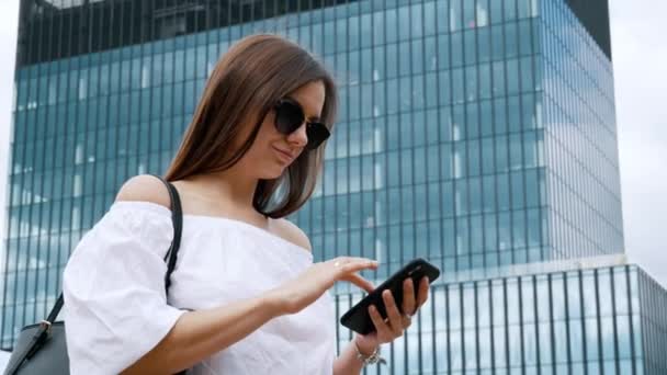 Уверенная предпринимательница пользуется мобильным телефоном на фоне здания — стоковое видео