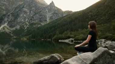 Sağlıklı kadın bir dağ gölü üzerinde meditasyon, yoga pratik, dağlarda yüksek huzur sahiptir
