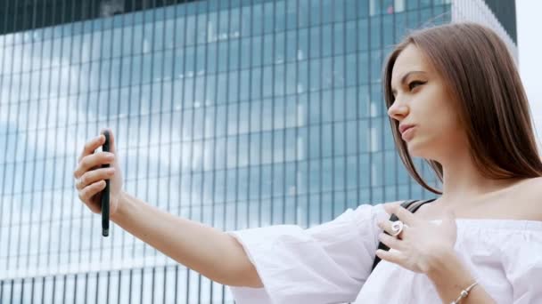 Une femme d'affaires prospère tient le téléphone dans sa main et parle par vidéoconférence, vidéoconférence, bureau en arrière-plan — Video