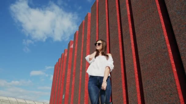 Felice bella donna si trova sulla strada della città vicino a un moderno edificio in mattoni, centro espositivo — Video Stock