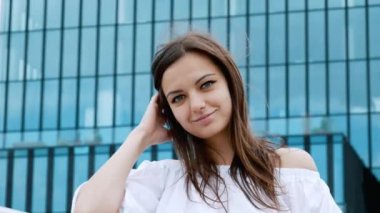 Güzel genç iş kadınının yakın çekim portresi sokakta kameraya gülümsüyor