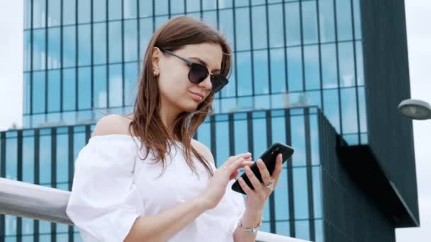 Современная молодая деловая женщина пользуется мобильным телефоном, пишет смс-ки, общается с коллегами, просматривает интернет — стоковое видео