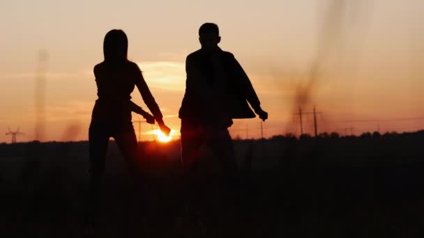 Силует божевільних, сучасних танців пари в полі на заході сонця — стокове відео