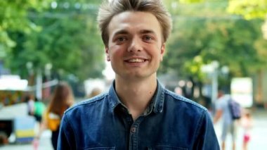 Mutlu ve çekici bir adamın hayat tarzı portresi. Gülümseyen ve sokakta kameraya bakan bir adam.