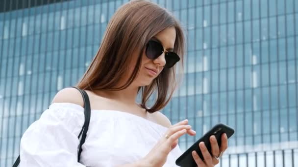 Mujer de negocios segura de usar el teléfono móvil en el fondo de un edificio — Vídeos de Stock