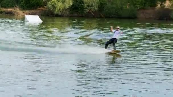 Extrem affärsman i kostym med slips och solglasögon rider på wakeboard på en sjö — Stockvideo