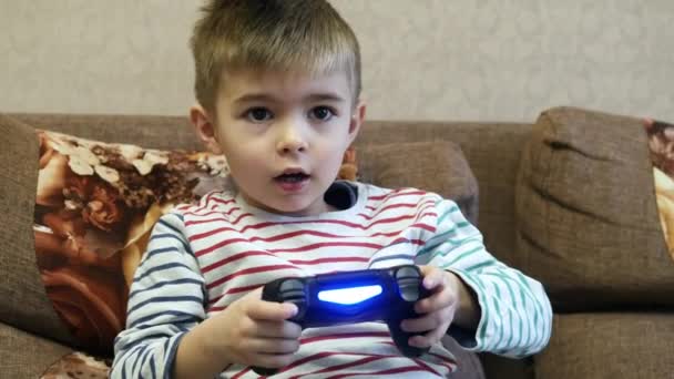 Mały chłopiec gra w gry wideo na kanapie w domu na wakacjach — Wideo stockowe
