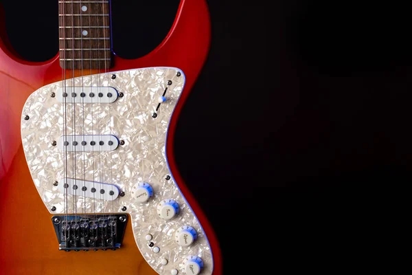 Instrumento musical de madera guitarra de seis cuerdas rojo aislado sobre fondo negro —  Fotos de Stock