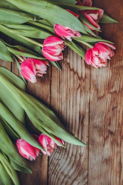 Laleler tahta bir masanın üzerinde yatıyor. Close. Ahududu çiçekleri. Pembe laleler. Tebrik kartları için arka plan.