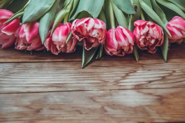 Laleler tahta bir masanın üzerinde yatıyor. Close. Ahududu çiçekleri. Pembe laleler.