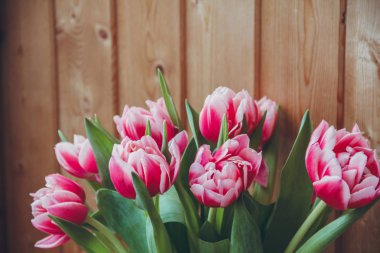 Pencerenin yanında vazoda laleler var. Pencerenin yanında ahşap bir masa üzerinde bir vazo içinde çiçek buketi.
