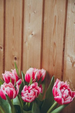 Pencerenin yanında vazoda laleler var. Pencerenin yanında ahşap bir masa üzerinde bir vazo içinde çiçek buketi.