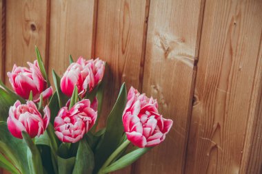 Pencerenin yanında vazoda laleler var. Pencerenin yanında ahşap bir masa üzerinde bir vazo içinde çiçek buketi.