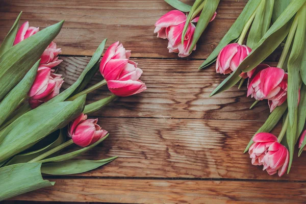 Laleler tahta bir masanın üzerinde yatıyor. Close. Ahududu çiçekleri. Pembe laleler.