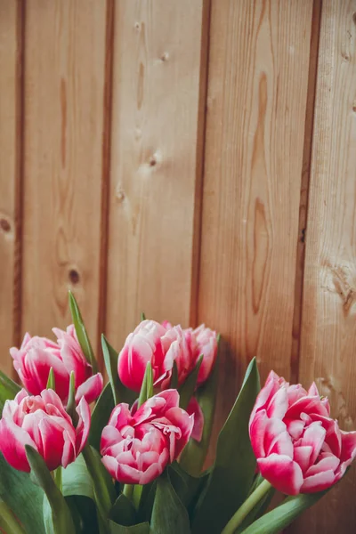 Pencerenin yanında vazoda laleler var. Pencerenin yanında ahşap bir masa üzerinde bir vazo içinde çiçek buketi.
