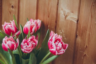 Pencerenin yanında vazoda laleler var. Pencerenin yanında ahşap bir masa üzerinde bir vazo içinde çiçek buketi.
