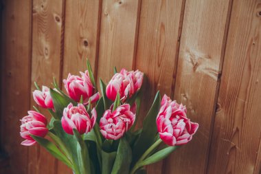 Tahta bir masada çiçek buketi. Vazoda laleler. Çiçek buketi üst görünümü.