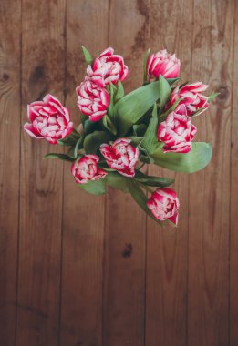 Tahta bir masada çiçek buketi. Vazoda laleler. Çiçek buketi üst görünümü.