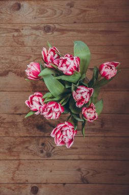 Tahta bir masada çiçek buketi. Vazoda laleler. Çiçek buketi üst görünümü.
