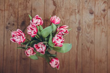 Tahta bir masada çiçek buketi. Vazoda laleler. Çiçek buketi üst görünümü.