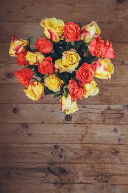 Tahta bir arka plan üzerinde gül buketi. Yukarıdan görüntüleyin. Sarı ve turuncu güller. Masada çiçek buketi.