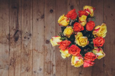 Tahta bir arka plan üzerinde gül buketi. Yukarıdan görüntüleyin. Sarı ve turuncu güller. Masada çiçek buketi.