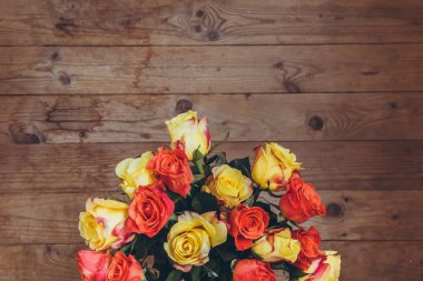 Tahta bir arka plan üzerinde gül buketi. Yukarıdan görüntüleyin. Sarı ve turuncu güller. Masada çiçek buketi.