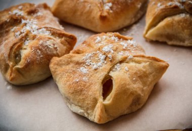 Elma çörekleri. Taze kek. Meyveli börekler tahta bir masanın üzerinde yatıyor.. 