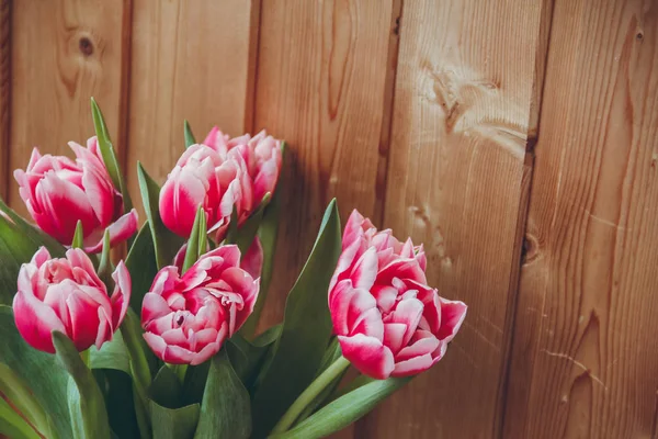 Pencerenin yanında vazoda laleler var. Pencerenin yanında ahşap bir masa üzerinde bir vazo içinde çiçek buketi.