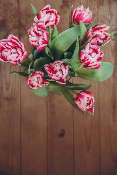 Tahta bir masada çiçek buketi. Vazoda laleler. Çiçek buketi üst görünümü.