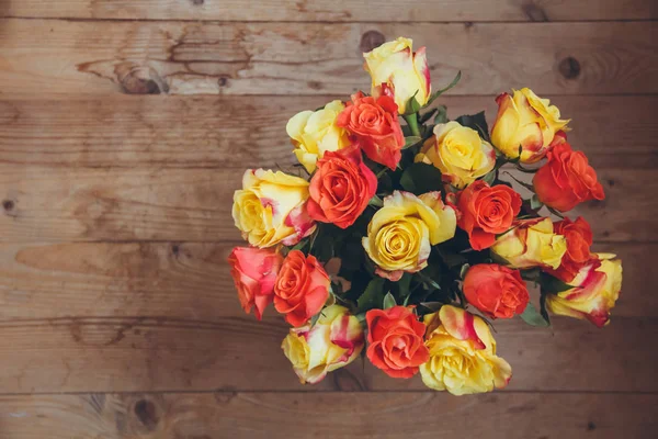 Tahta bir arka plan üzerinde gül buketi. Yukarıdan görüntüleyin. Sarı ve turuncu güller. Masada çiçek buketi.