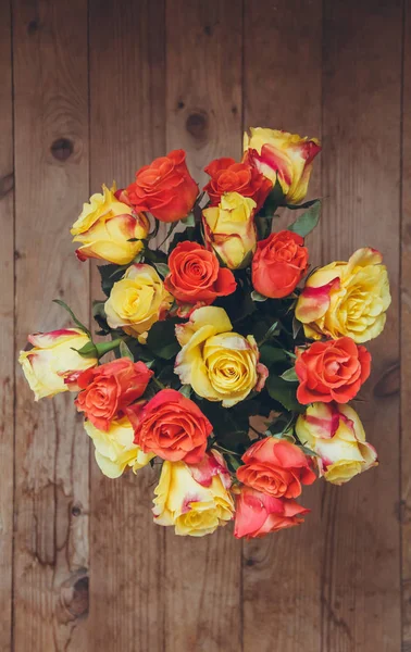 Ramo de rosas sobre fondo de madera. Vista desde arriba. Rosas amarillas y naranjas. Ramo de flores sobre la mesa . — Foto de Stock