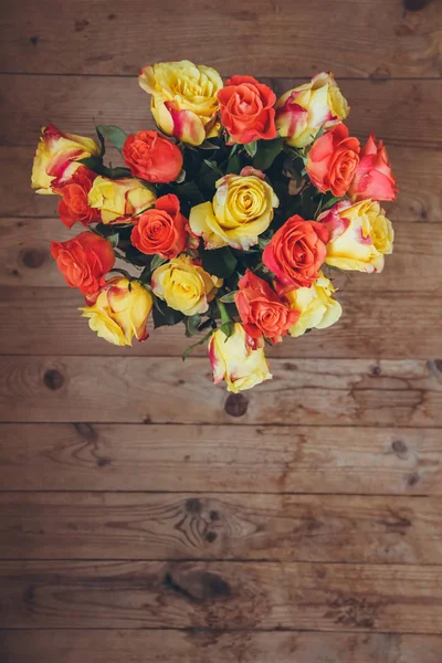 Tahta bir arka plan üzerinde gül buketi. Yukarıdan görüntüleyin. Sarı ve turuncu güller. Masada çiçek buketi.