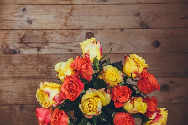 Tahta bir arka plan üzerinde gül buketi. Yukarıdan görüntüleyin. Sarı ve turuncu güller. Masada çiçek buketi.