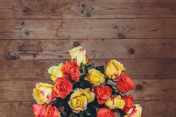 Tahta bir arka plan üzerinde gül buketi. Yukarıdan görüntüleyin. Sarı ve turuncu güller. Masada çiçek buketi.