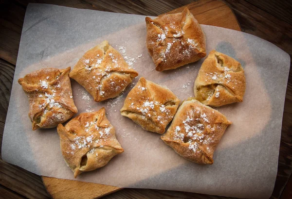 Elma çörekleri. Taze kek. Meyveli börekler tahta bir masanın üzerinde yatıyor.. 