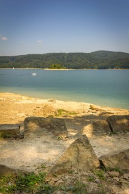 Bieszczady Dağları, Polonya. Solina Gölü. Gölün manzarası, uzaktaki yelkenliler. Gölün kıyısındaki kayalar.