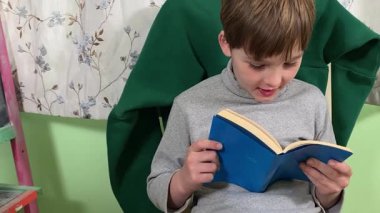 Okul çağındaki çocuk evde ders çalışıyor, ödevlerini özveriyle yapmaya odaklanmış. Öğrenmeyi destekleyen sakin bir ortamda okuma ve sayma, bilgi ve beceriler geliştirme pratiği yapıyor.. 