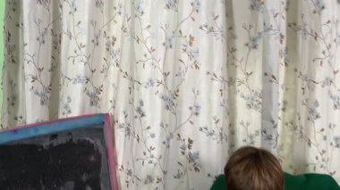 Okul çağındaki çocuk evde ders çalışıyor, ödevlerini özveriyle yapmaya odaklanmış. Öğrenmeyi destekleyen sakin bir ortamda okuma ve sayma, bilgi ve beceriler geliştirme pratiği yapıyor.. 